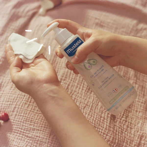 Close-up of a hand holding a baby lotion bottle, reading the ingredient list on the back label"